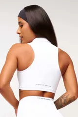 Top deportivo negro, estilo crop top, con cuello polo y escote en V. Presenta tirantes anchos y corte ajustado al cuerpo.