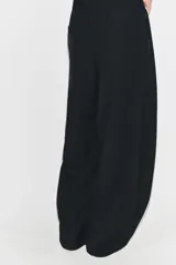 Pantalón negro de tiro alto y pernera ancha, confeccionado en tejido fluido, con bolsillos laterales y detalles de pliegues en la parte delantera.