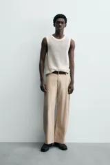 Chaleco de punto color blanco roto, con cuello redondo y sisa, confeccionado en tejido calado de estructura abierta y acabado en rib.