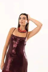 Vestido corto de tirantes finos en color bordó con acabado metalizado brillante. Presenta un corte recto ajustado al cuerpo y un detalle de volado en el ruedo confeccionado en tela traslúcida.