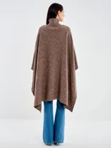 Poncho de lana color marrón con cuello alto acanalado y silueta amplia. Presenta un tejido de punto con diseño texturizado de rombos y caída relajada.