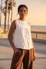 Blusa sin mangas de algodón color blanco, con cuello redondo, detalles de encaje y diseño fruncido en el frente.