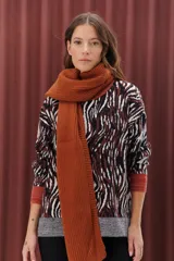 Sweater de punto con estampado animal print en tonos marrones, negros y blancos. Tiene cuello redondo, puños y bajo acanalados en color marrón y gris.