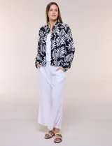Camperita de lino liviana, marca Dash, con estampado botánico de hojas en tonos azules, verdes y tostados sobre base blanca. Presenta cierre frontal con botones, cuello clásico y bolsillos aplicados en el pecho.