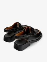 Zapato de cuero vacuno negro, con cordones y talón descubierto.