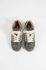 Zapatilla de estilo retro en combinación de colores verde, blanco y gris. Presenta un diseño de paneles superpuestos con texturas lisas y gamuzadas, cordones al tono y suela plana de goma.