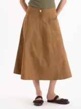 Pollera midi de silueta en A color marrón, con bolsillos ocultos en los laterales, recortes verticales y cierre frontal con botón personalizado.