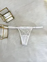 Tanga blanca de encaje con elástico ancho regulable y entrepierna de algodón.