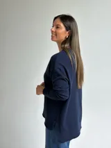 Sweater de punto en color azul marino, con escote en V, manga larga con puños acanalados y costura central vertical en el frente.