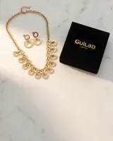 Set de joyería compuesto por un collar de cadena con eslabones circulares entrelazados y aros colgantes a juego con diseño de doble círculo, ambos con acabado en tono dorado.
