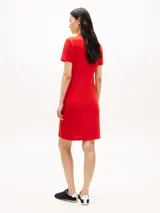 Vestido tipo chomba de color rojo, con corte slim y largo hasta la rodilla. Cuenta con mangas cortas, cuello polo y escote en V pronunciado. Presenta detalle de logo bordado en la manga.