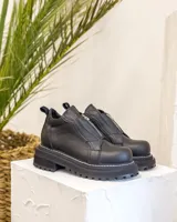 Botinetas de cuero combinadas en color negro y marrón, con diseño de paneles, cierre frontal y suela track dentada.