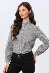 Camisa de algodón celeste con estampado floral pequeño, cuello mao, mangas largas con puños fruncidos y cierre frontal de botones.