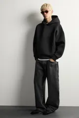 Sudadera negra de corte boxy fit, confeccionada en tejido compacto con elasticidad. Presenta capucha, manga larga, bolsillo frontal tipo canguro y acabados en rib.