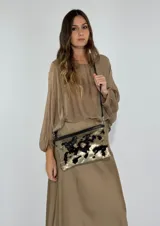 Cartera tipo sobre con lentejuelas doradas y negras reversibles, con borde superior de cuero negro y correa fina de cuero negro.