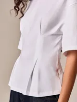 Top blanco de diseño estructurado, con mangas amplias y silueta entallada mediante pinzas frontales. Confeccionado en tela de algodón con caída firme y acabado minimalista.
