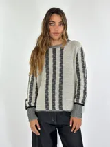 Sweater de punto color crema con rayas verticales negras y mangas largas.