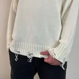 Sweater de tejido de punto color blanco, con diseño de cuello redondo y detalles de roturas desgastadas en el cuello, puños y ruedo.