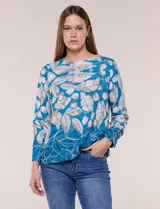 Blusa de silueta holgada y corte recto con caída fluida, escote redondo clásico y mangas largas con puños anchos estructurados. Cuenta con estampado de hojas y ramas en tonos blancos y marrones sobre fondo turquesa.