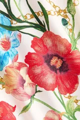 Remera oversized de algodón color blanco, con cuello redondo, mangas cortas y hombros caídos. Presenta un estampado frontal con la palabra 'Fiori', ilustraciones de flores coloridas y cadenas doradas.