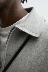 Polo de punto de corte relajado, confeccionado en mezcla de algodón, con cuello solapa, cierre frontal de cremallera y manga larga con acabados en rib.