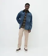 Campera de jean de corte oversized, con cuello de terciopelo, cierre frontal por botones y bolsillos grandes aplicados en el frente.