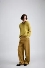 Pantalón de tiro medio confeccionado en tejido de pana, con diseño de pierna ancha, bolsillos delanteros y traseros, y cierre frontal con cremallera y botón.
