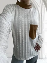 Polera blanca de tejido trenzado con cuello alto de cuero marrón y bolsillo de cuero marrón con textura de cocodrilo.