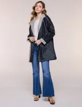 Pilot engomado impermeable color azul, de corte recto estilo trench con acabado resistente al agua. Cuenta con capucha integrada, cierre frontal con broches a presión, bolsillos laterales con ojal y forro interior de tela estampada a cuadros visible en la solapa y los puños.