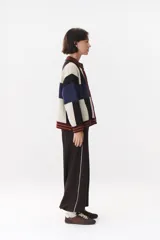Cardigan de punto con diseño de bloques de color en tonos marrón, beige y verde. Presenta cuello redondo, cierre frontal con botones, mangas largas con hombros caídos y logo bordado en el frente.