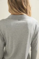Conjunto de pijama compuesto por una camisa de manga larga con cuello solapa y cierre frontal de botones, y un pantalón de corte recto. Ambas prendas están confeccionadas en tejido de punto acanalado de color gris claro.