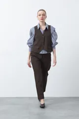 Chaleco sastrero color marrón oscuro, con escote en V, cierre frontal de botones y pinzas de entalle.