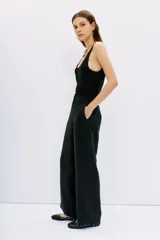 Pantalón palazzo negro de tiro alto, confeccionado en cupro y viscosa, con bolsillos diagonales laterales, bolsillos ojal falsos en la espalda y cierre lateral invisible.