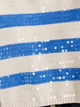 Sweater crop de cuello tortuga, color blanco con rayas azules y aplicación de lentejuelas, manga larga y tejido extra suave de media estación.