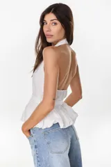 Blusa blanca de corte peplum con diseño halter y espalda descubierta.