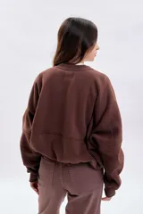 Campera oversize color marrón con cierre frontal, mangas amplias y diseño con cortes horizontales. Presenta puños y ruedo acanalados.