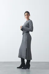 Vestido midi de punto en color gris, con diseño de tejido acanalado vertical, cuello redondo y mangas largas. Presenta una silueta recta y fluida.