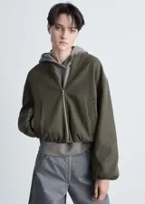 Chaqueta tipo bomber de tejido ligero en color verde oliva, con diseño oversize, cierre frontal de cremallera, bolsillos laterales y bajo con detalle fruncido. Presenta mangas largas con puños elásticos y fruncidos.