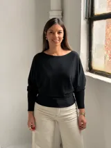 Sweater negro de punto con diseño de mangas tipo murciélago, cuello redondo y puños ajustados. Presenta un sutil patrón de líneas verticales en el tejido.