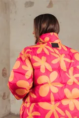 Campera puffer acolchada con estampado floral en tonos fucsia y naranja, cuello alto y cierre frontal.