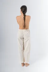 Pantalón de algodón color crudo con rayas verticales finas en beige, corte recto, cintura con elástico y detalle de puntilla en cintura y ruedo.