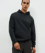 Buzo deportivo de hombre confeccionado en tejido polar (fleece) de color gris oscuro. Presenta capucha con cordones ajustables, bolsillo tipo canguro frontal, mangas largas con puños ajustados y bajo elástico. Su diseño es cerrado y cuenta con una textura suave y cálida ideal para el invierno.