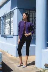 Cardigan de punto en color violeta con destellos de lurex, diseño de manga larga y cierre frontal con lazos. Presenta detalles de mostacillas en el ruedo.