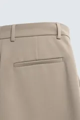 Pantalón de corte relajado en color verde militar, con diseño de pliegues frontales, bolsillos laterales y cierre de cremallera con botón.