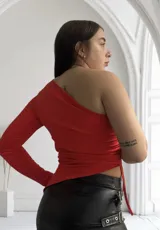 Top rojo de un solo hombro con manga larga en un brazo y detalle de lazo en el lateral.