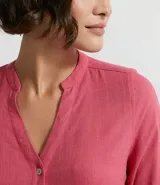 Camisa de manga larga confeccionada en mezcla de viscosa y lino, con cuello tipo padre, escote en V y cierre frontal con botones. Presenta un diseño con dobladillo tipo mullet, siendo más largo en la parte posterior.