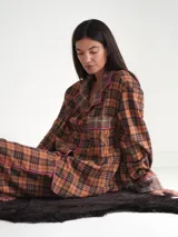 Conjunto de pijama a cuadros con ribetes en color lila, compuesto por camisa de manga larga con botones y pantalón largo.