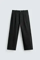Pantalón de corte balloon fit y estilo relajado, confeccionado en tejido de algodón. Presenta pliegues frontales, cintura con trabillas, cierre frontal con cremallera y botón, bolsillos delanteros y bolsillos traseros de vivo.
