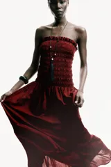 Vestido midi strapless de color bordó, con cuerpo fruncido elástico y falda larga acampanada con un volante en el bajo.