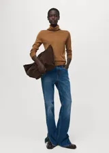 Sweater de punto fino color mostaza, con cuello alto y mangas largas de diseño recto.